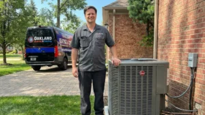 Oakland Heating and Cooling technician standing next to a new Rheem air conditioner installation at an Oakland County home