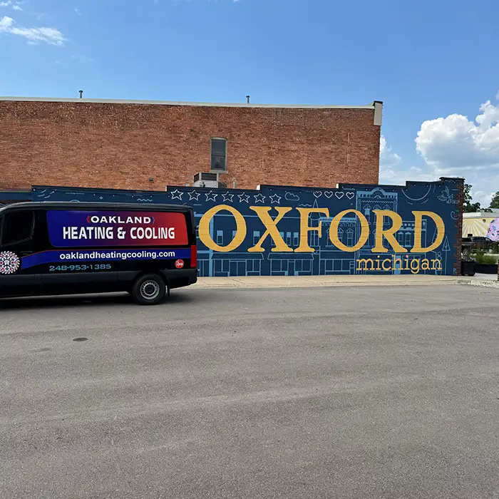 Oakland Heating & Cooling technician repairing an air conditioner in Oxford, MI